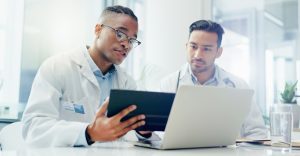 Two healthcare providers collaborating at a computer while exploring a q-centrix alternative for clinical data management.