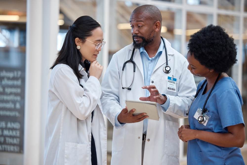 Physicians analyzing healthcare records together using a q-centrix alternative on a hospital workstation.
