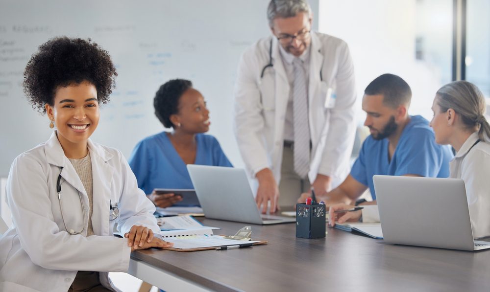 Doctors reviewing patient records and discussing registry management software on a computer in a modern healthcare office.
