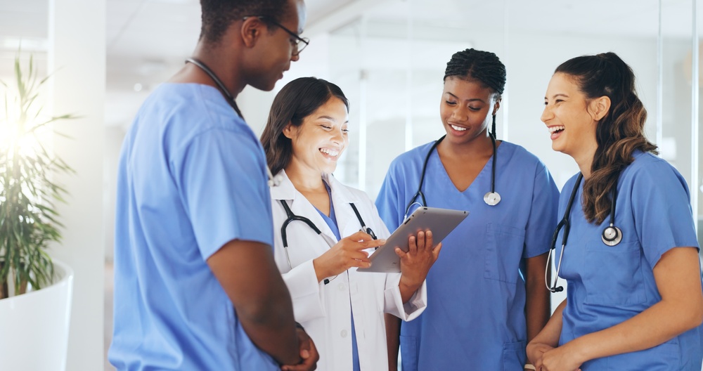 Healthcare professionals talking and looking at a computer screen displaying registry management software for patient data management.
