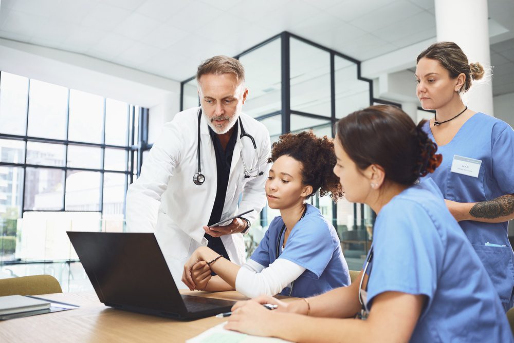 Doctors collaborating at a computer and evaluating patient information through registry management software in a healthcare setting.